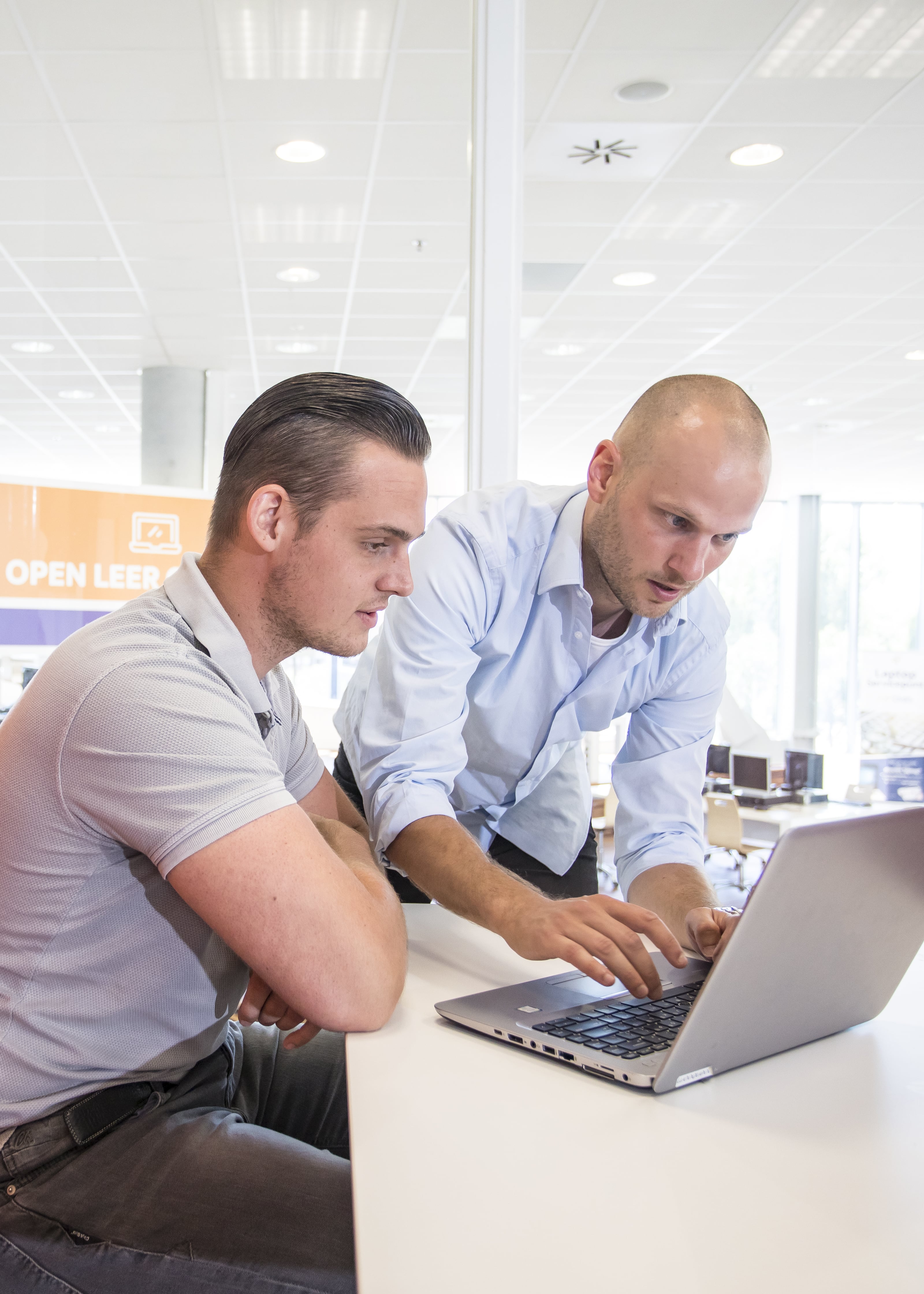 Docent legt uit aan student met laptop