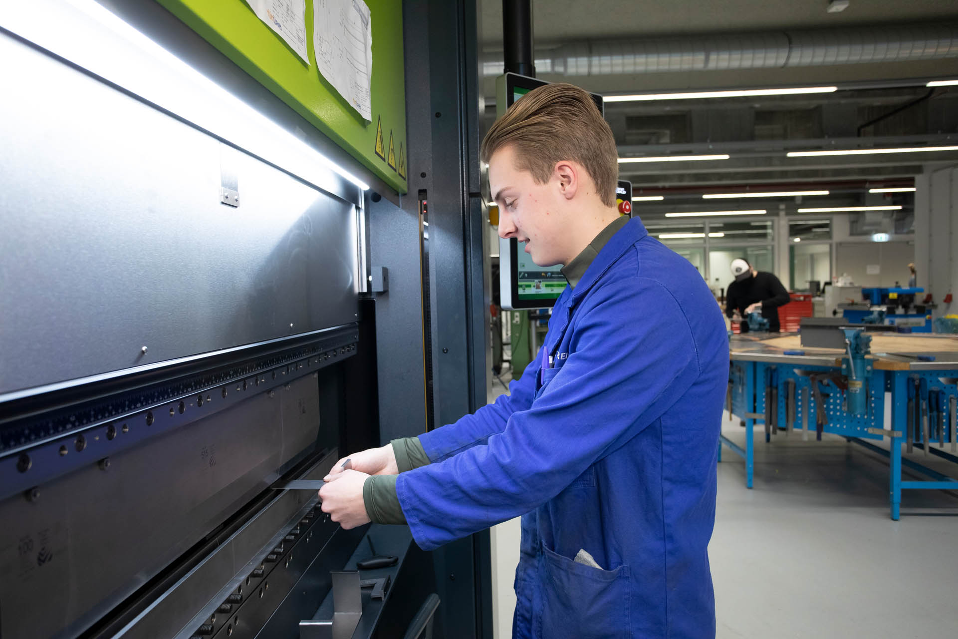 Student houdt stuk metaal vast bij machine