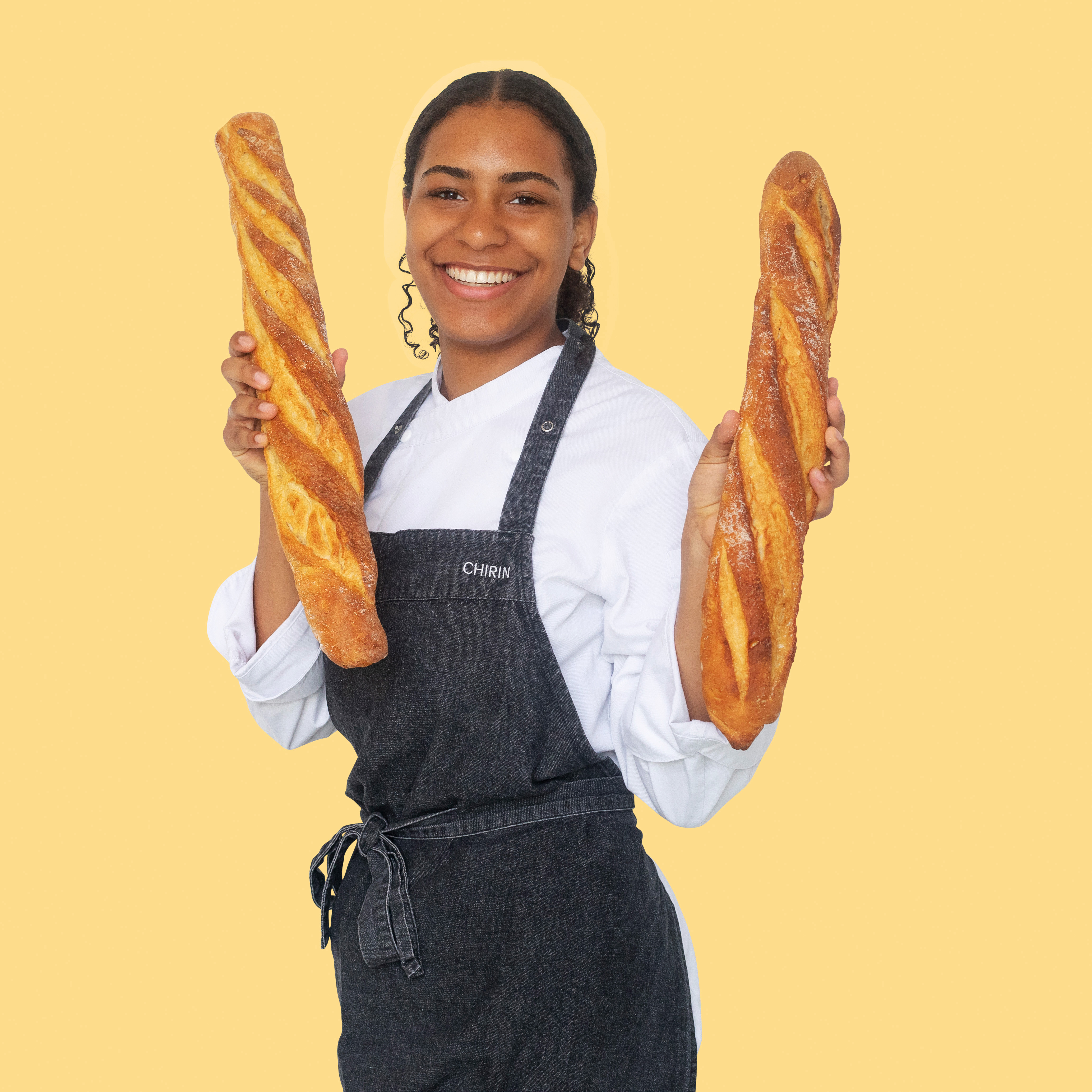 Meisje in bakkerskleding houdt twee stokbroden vast