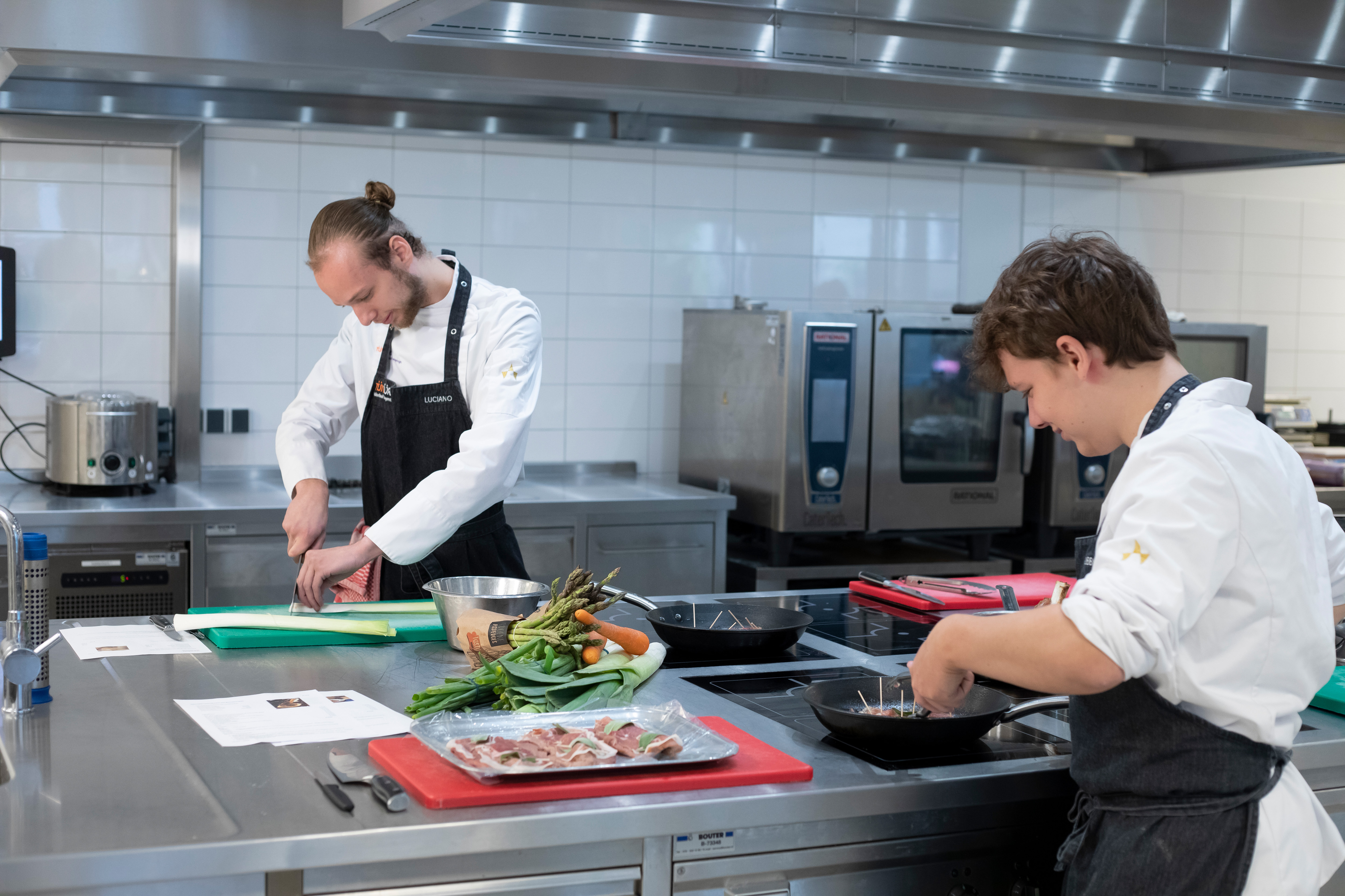 Twee jongens in kokskleding zijn aan het koken