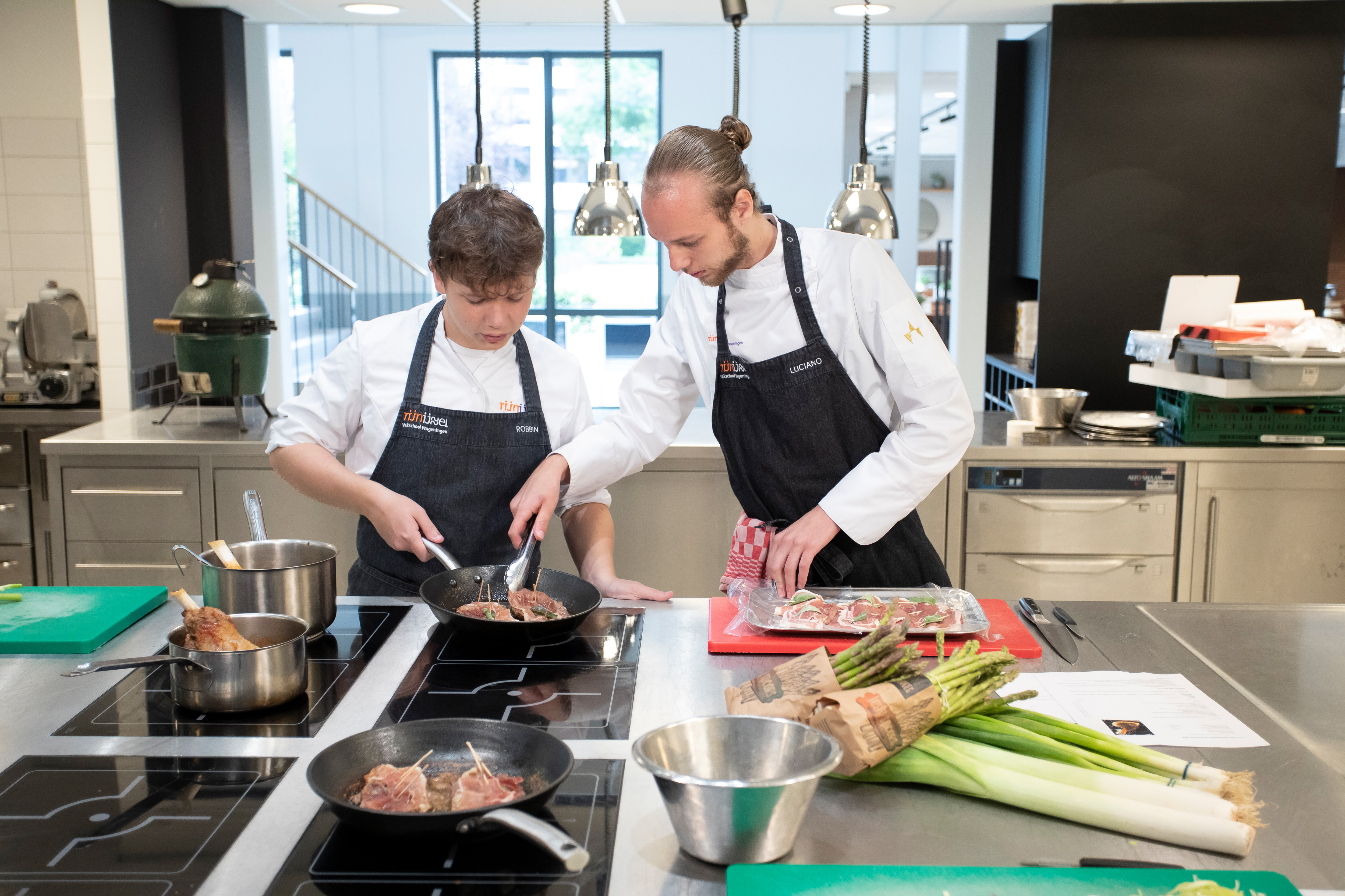 Twee jongens zijn aan het koken. Een van de jongens laat de andere zien hoe je moet koken