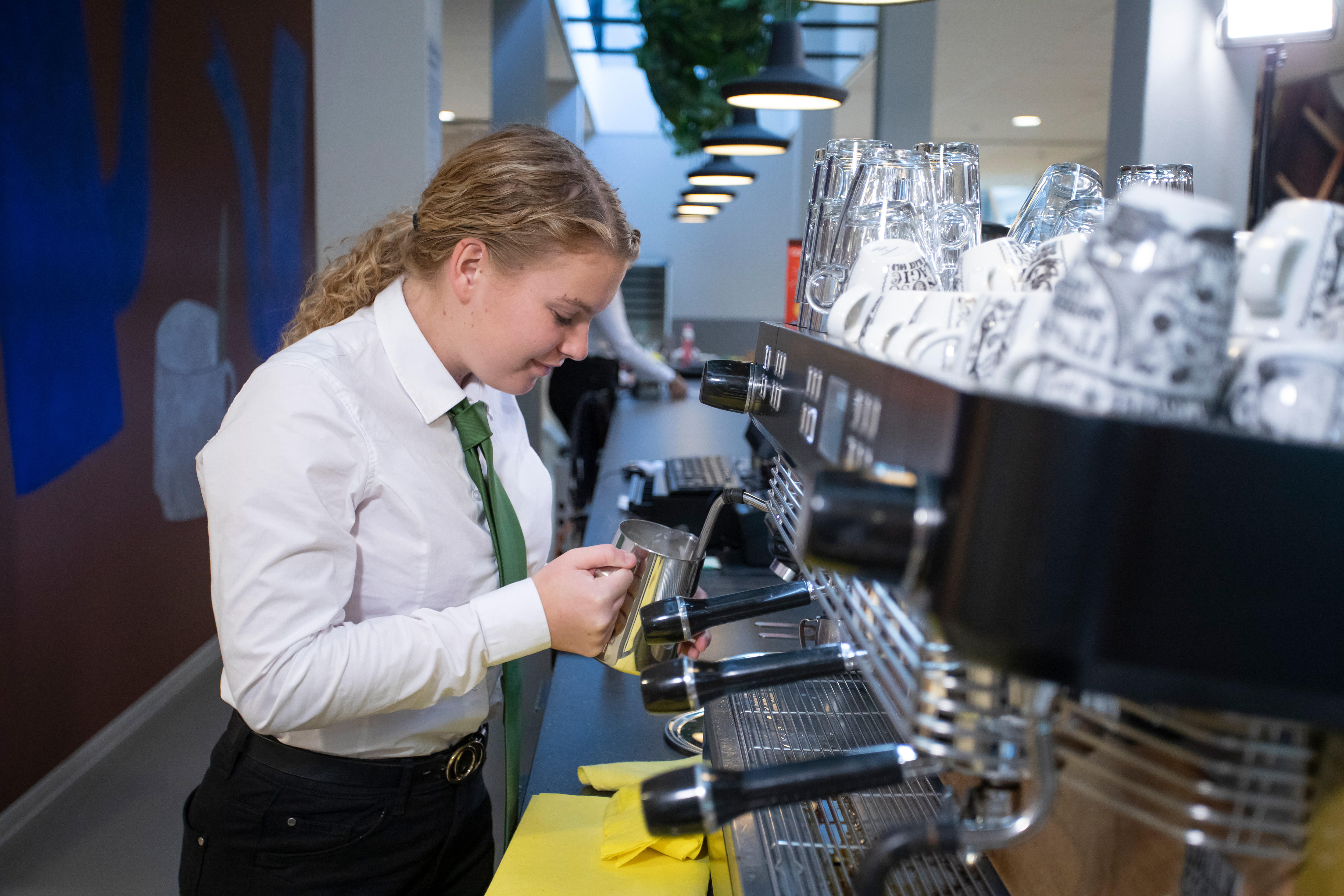 Meisje is melk aan het opschuimen voor de koffie