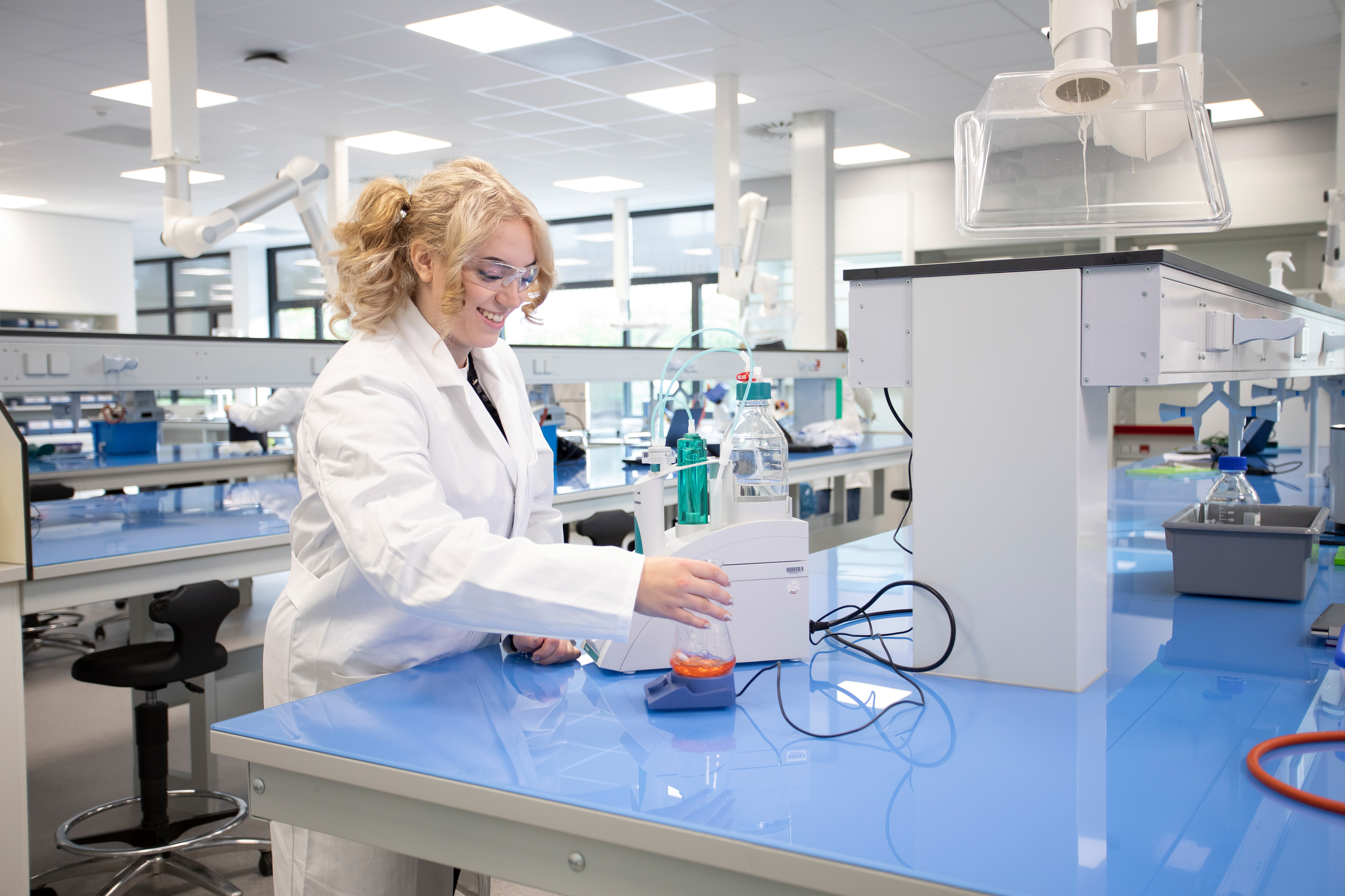 Student in een witte laboratoriumjas is bezig met een proef