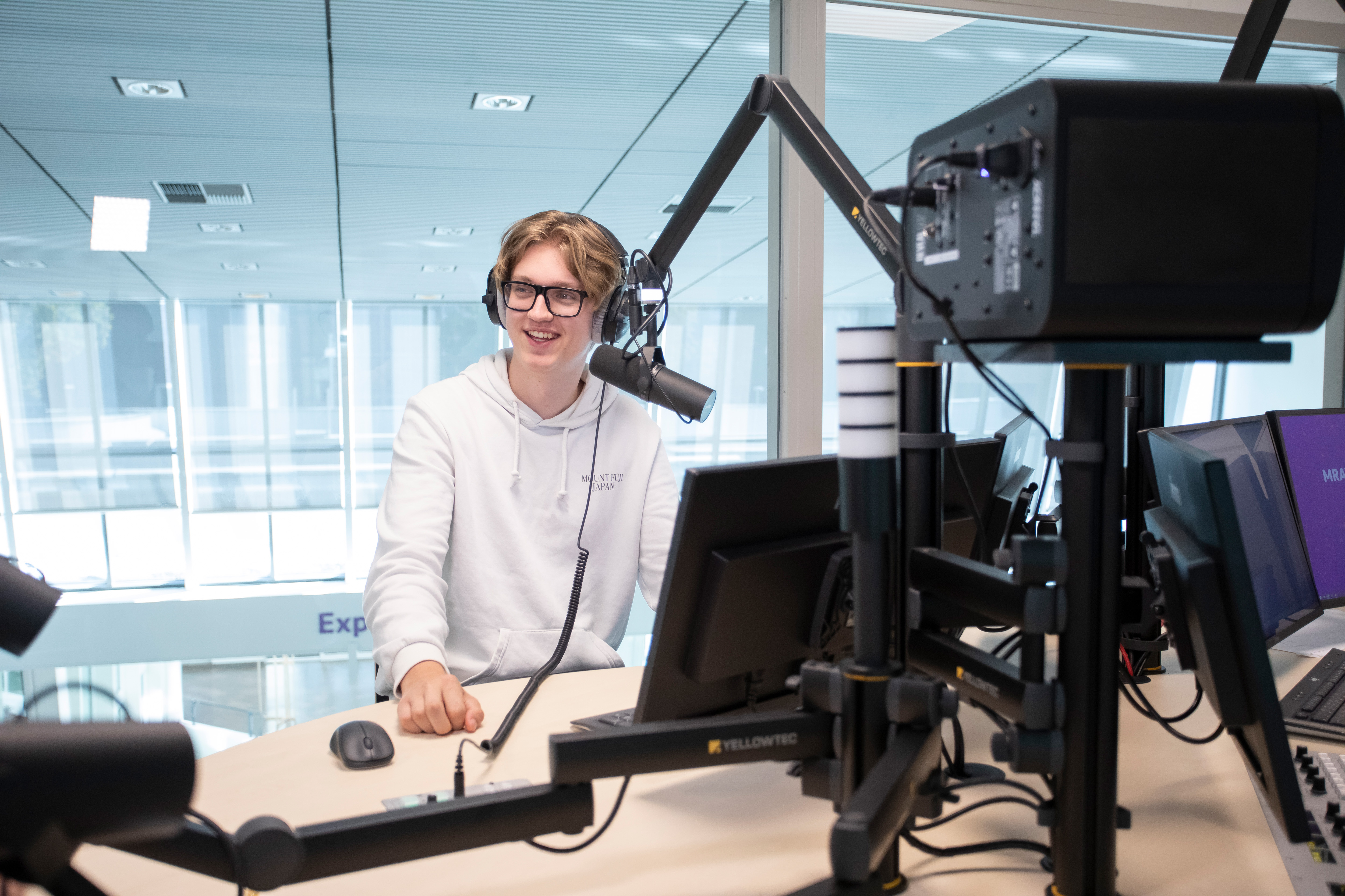 Student zit achter een microfoon met een koptelefoon op