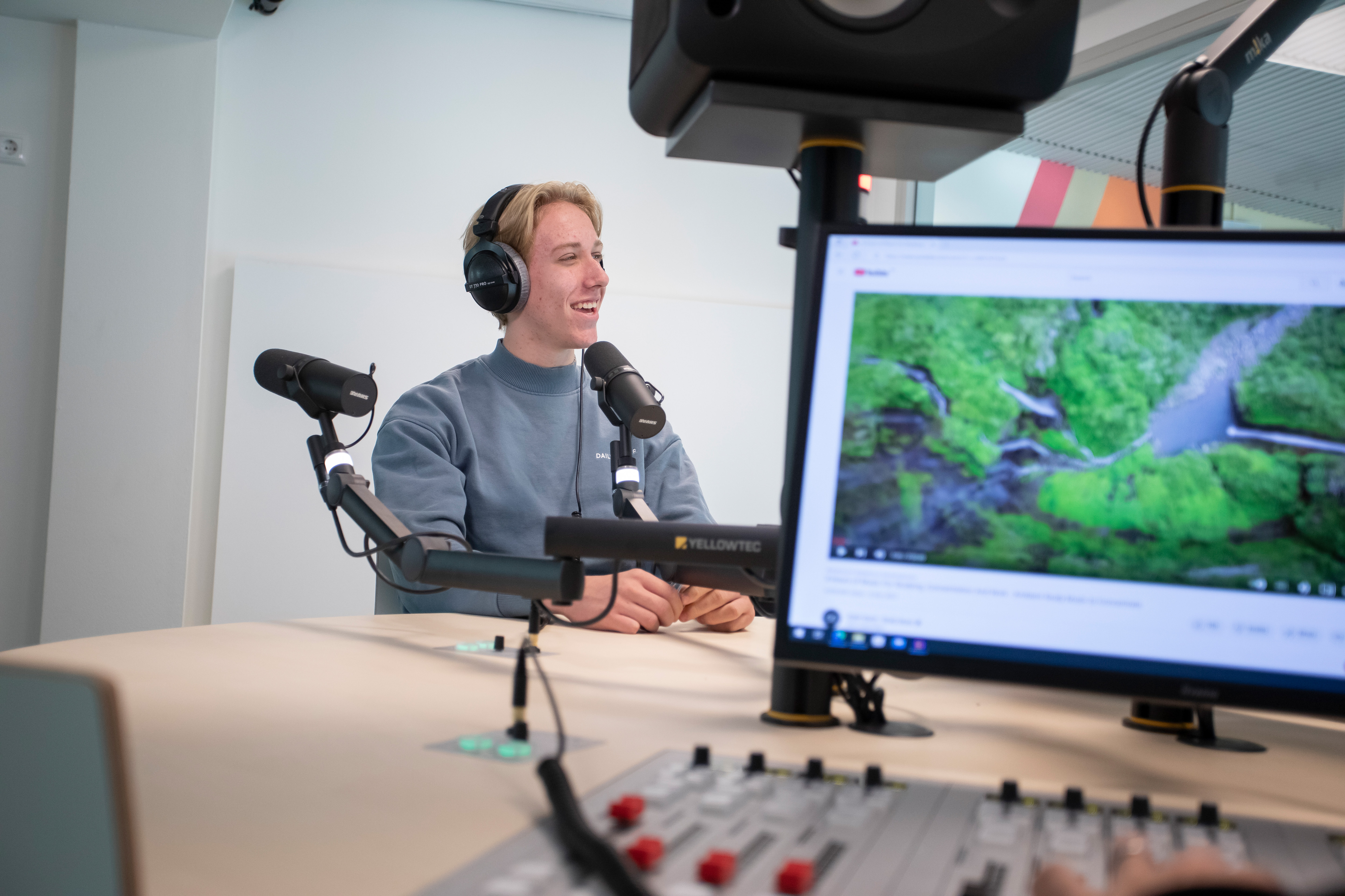 Student zit achter een microfoon met een koptelefoon op