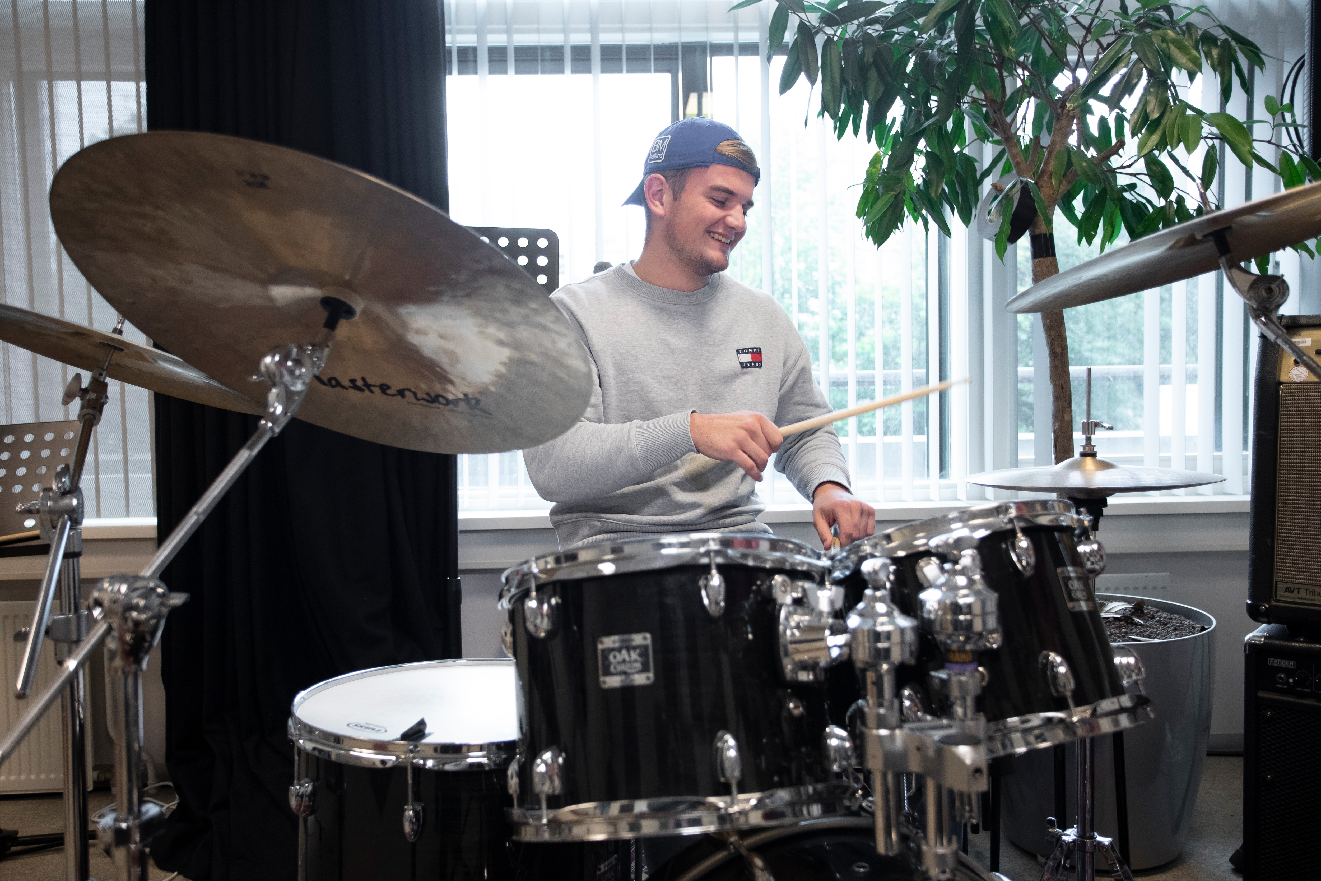 Student zit achter een drumstel en is aan het drummen