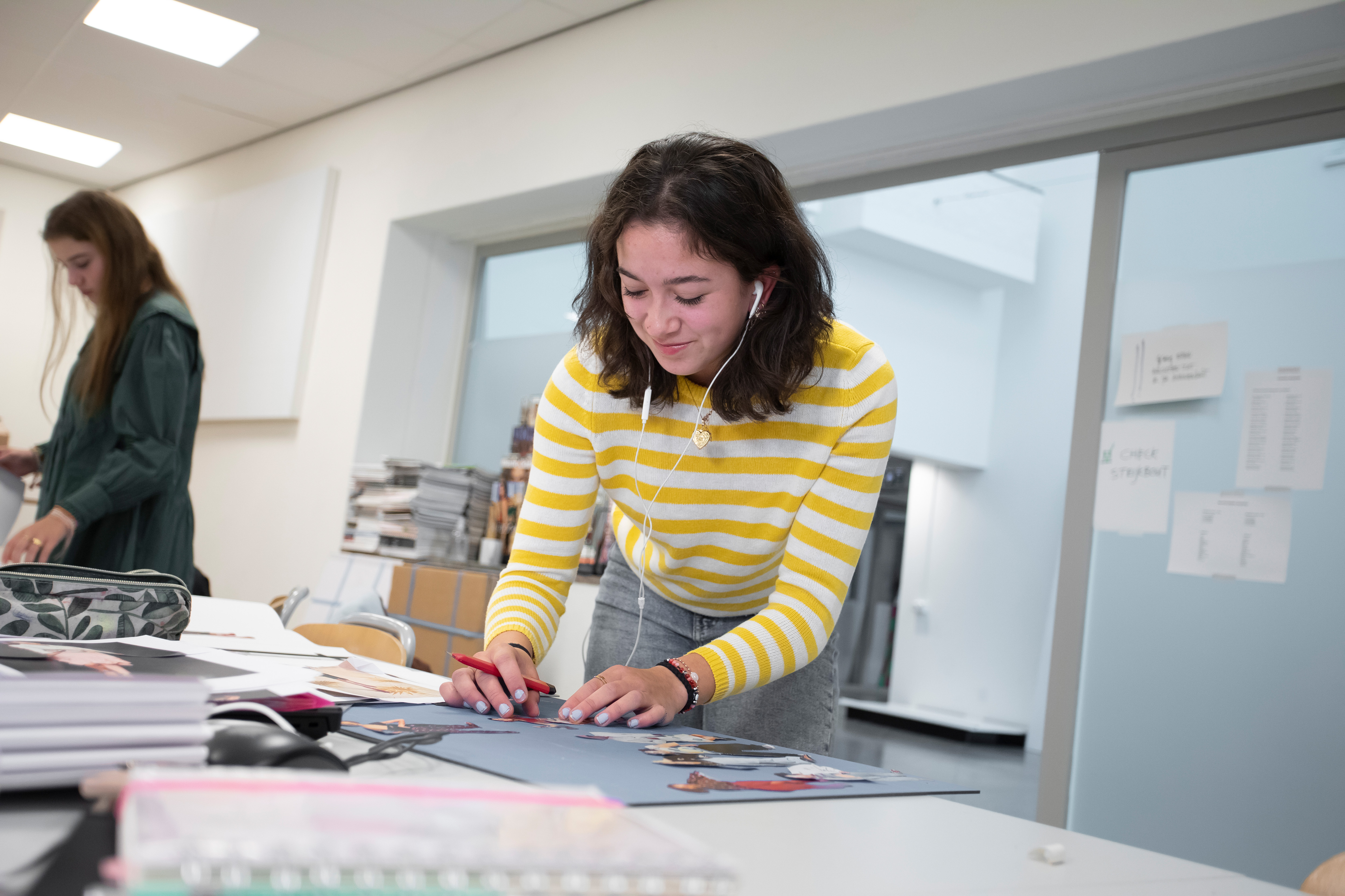 Student is bezig met uitknipsels op een bord te plakken