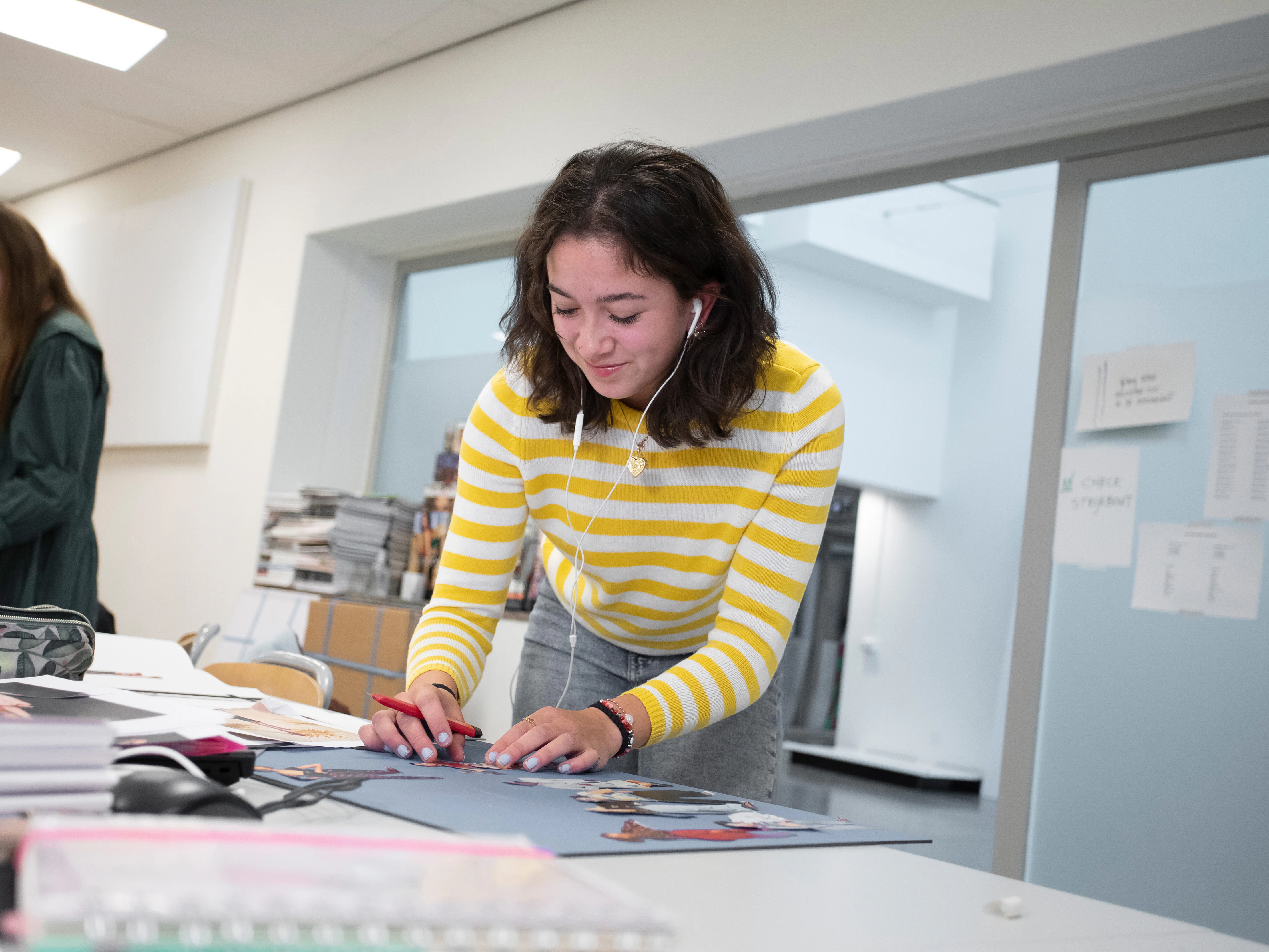 Student is bezig met uitknipsels op een bord te plakken