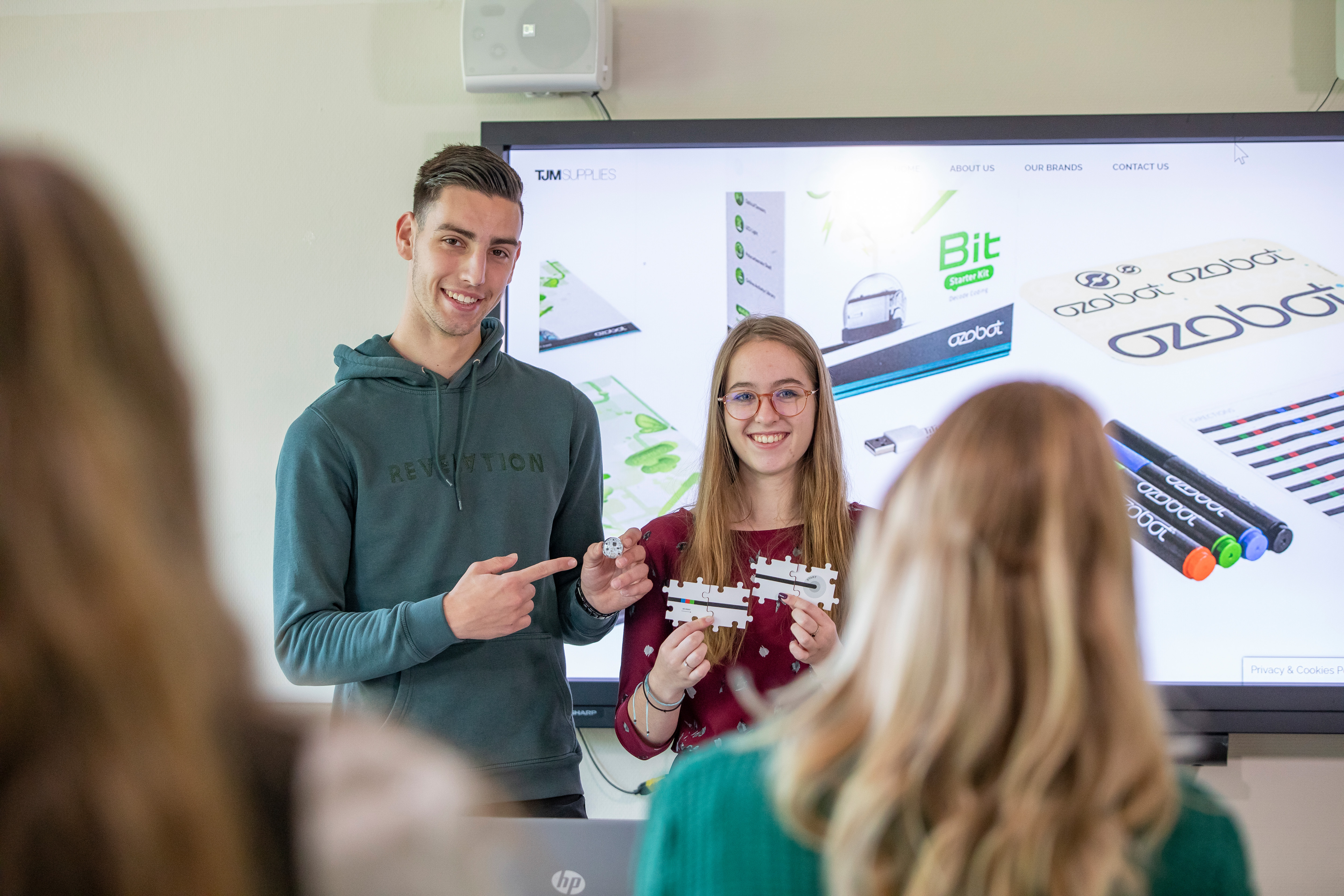 Twee studenten staan voor de klas