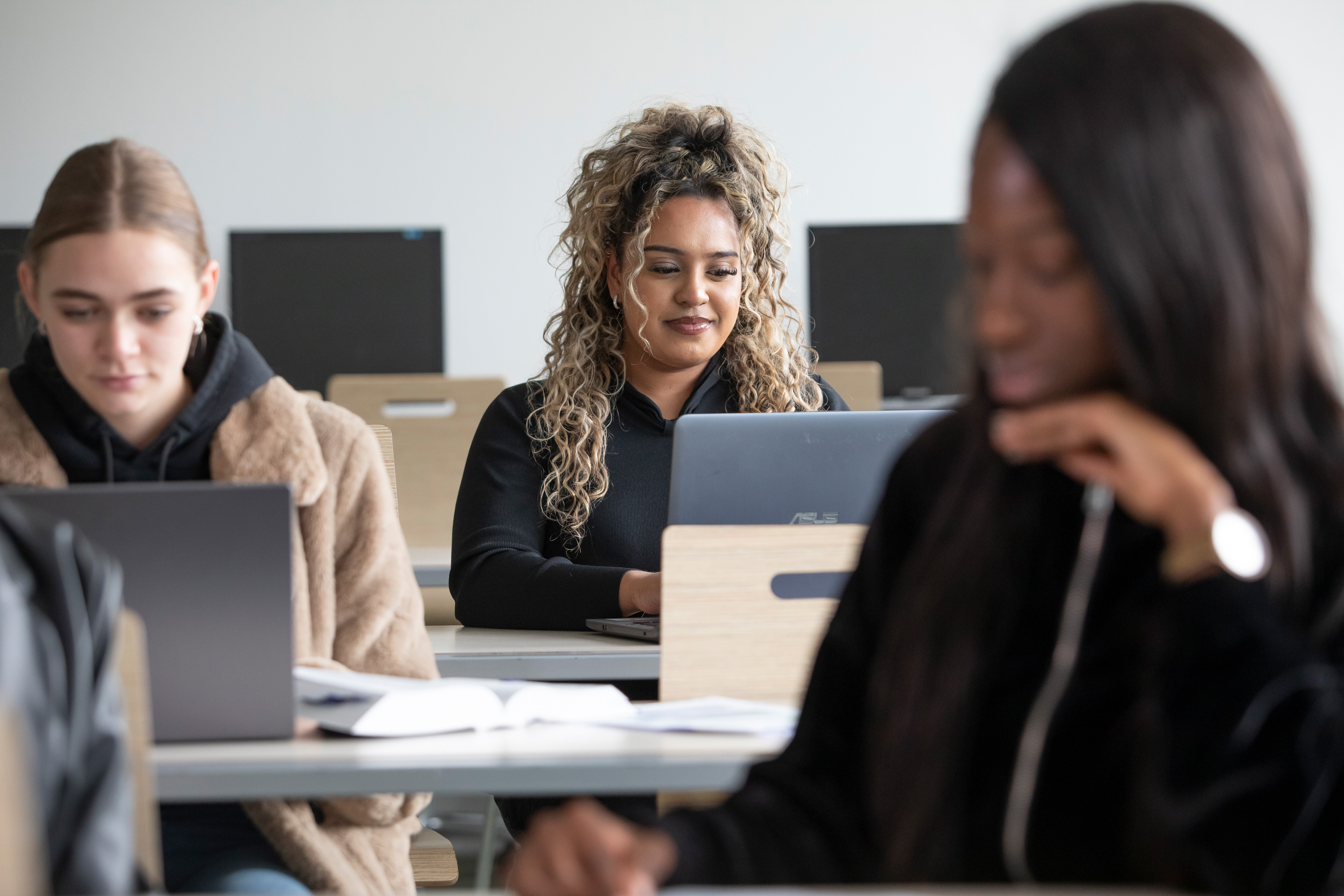 Drie studenten werken in klas op laptop
