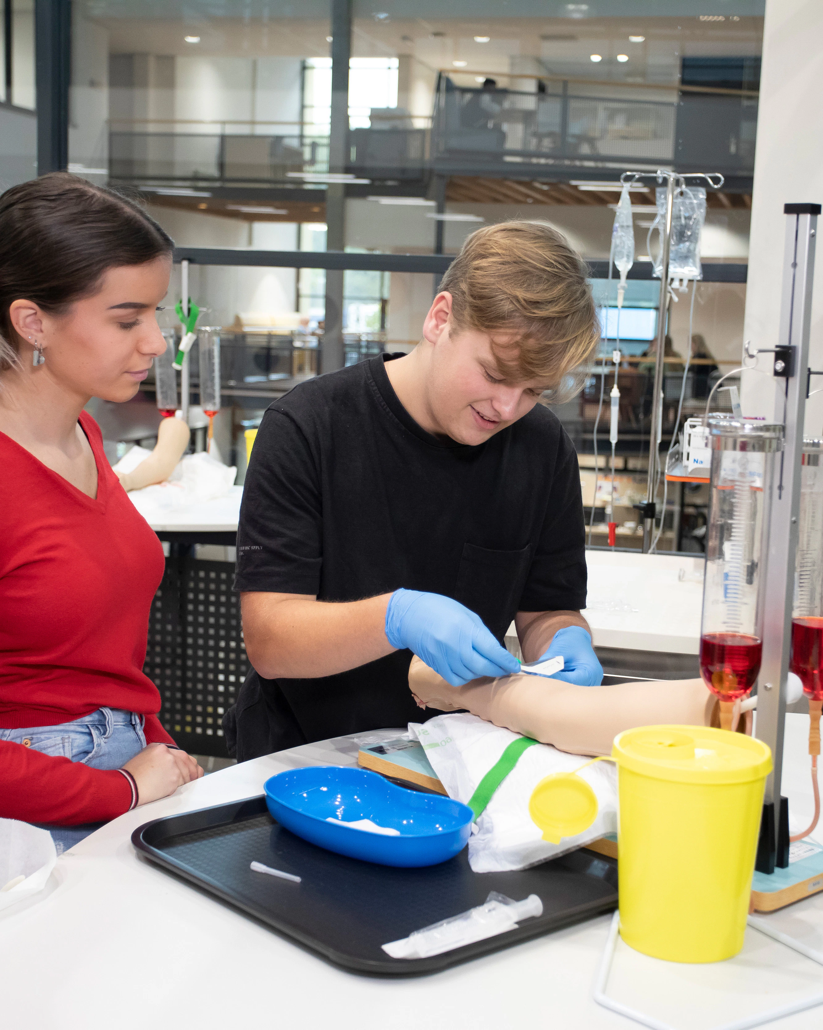 Student plakt een pleister op een been terwijl een student toekijkt
