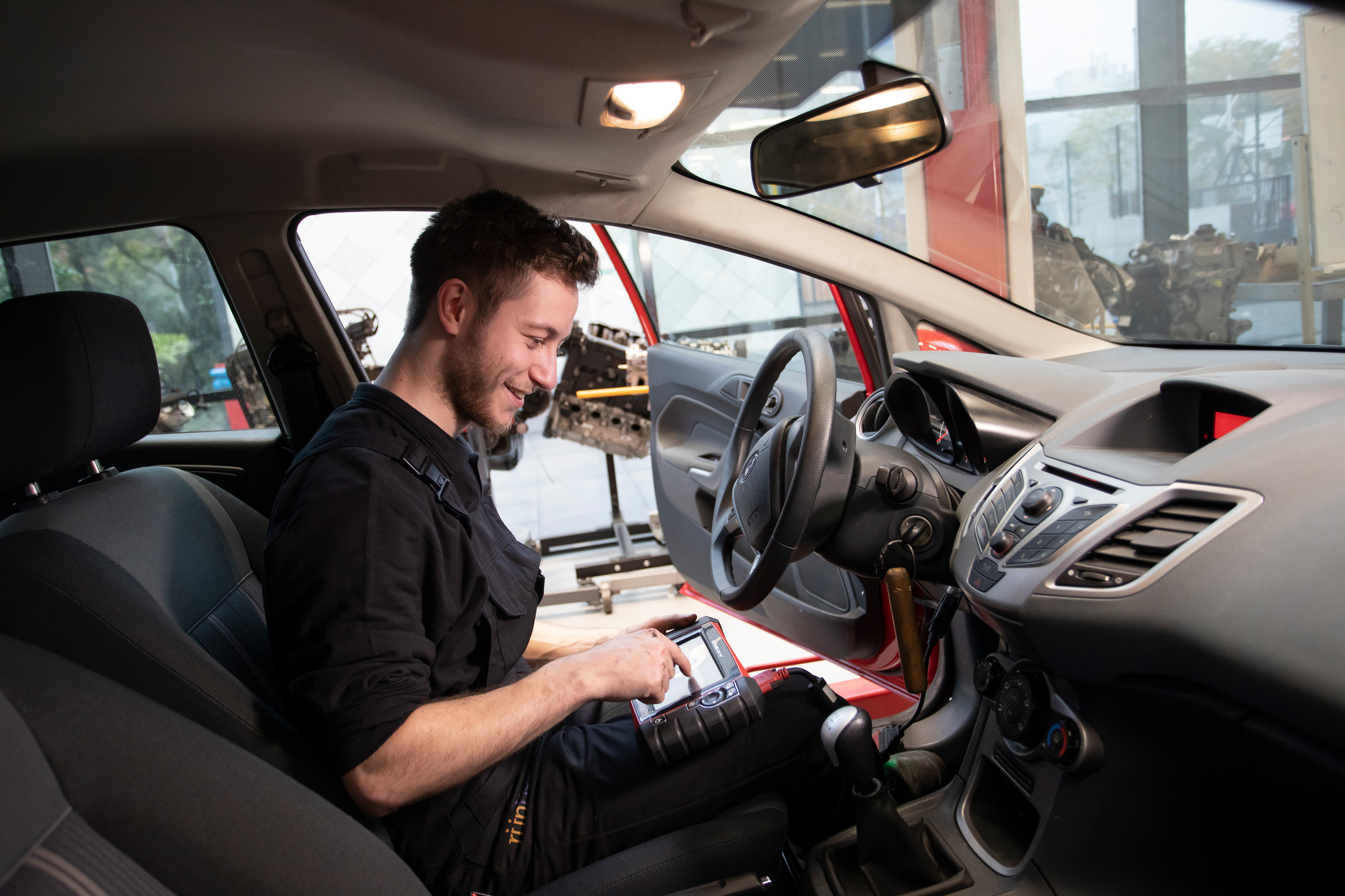 Student zit in een auto en houdt een scherm vast