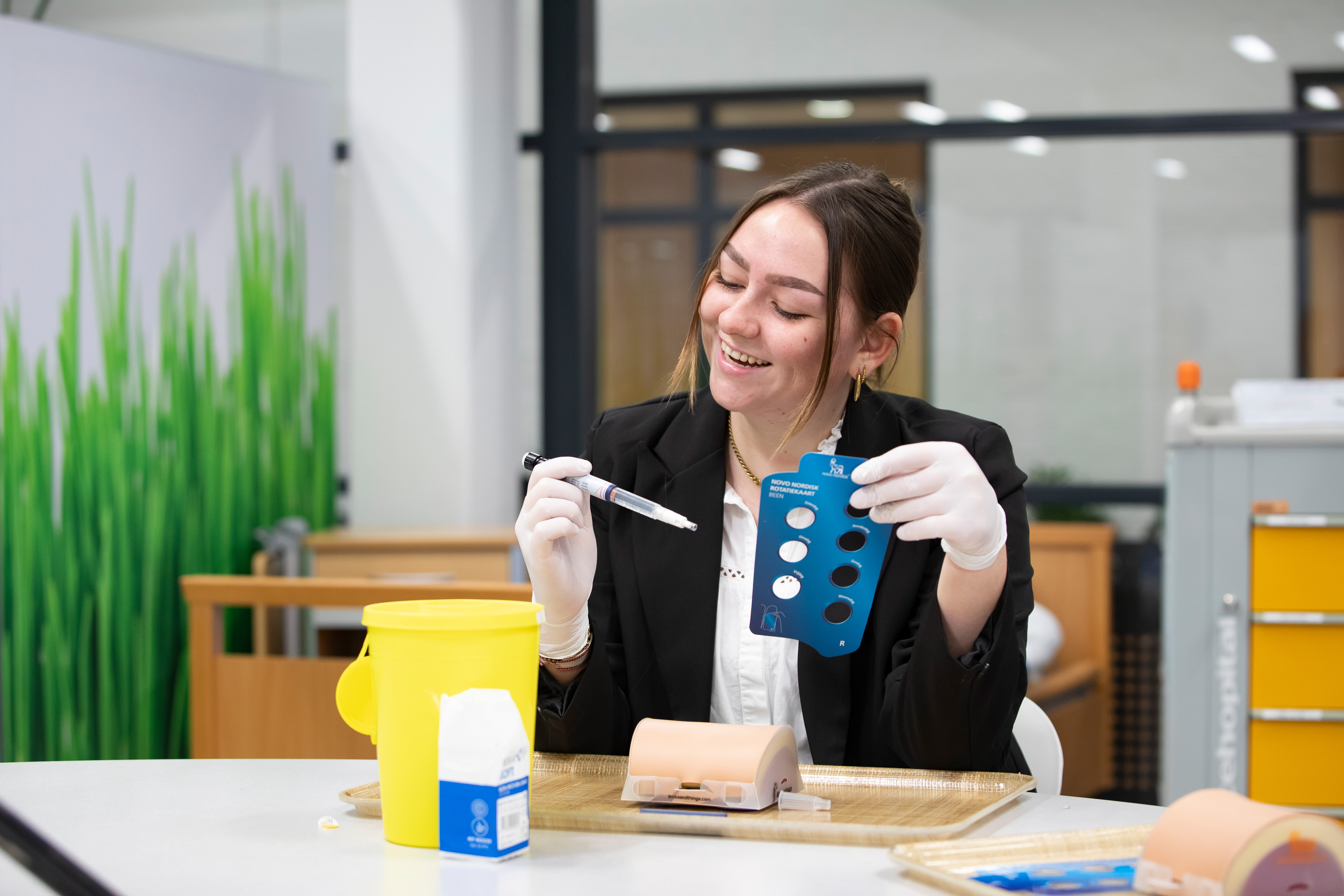 Student heeft een spuit in de hand en zit aan tafel
