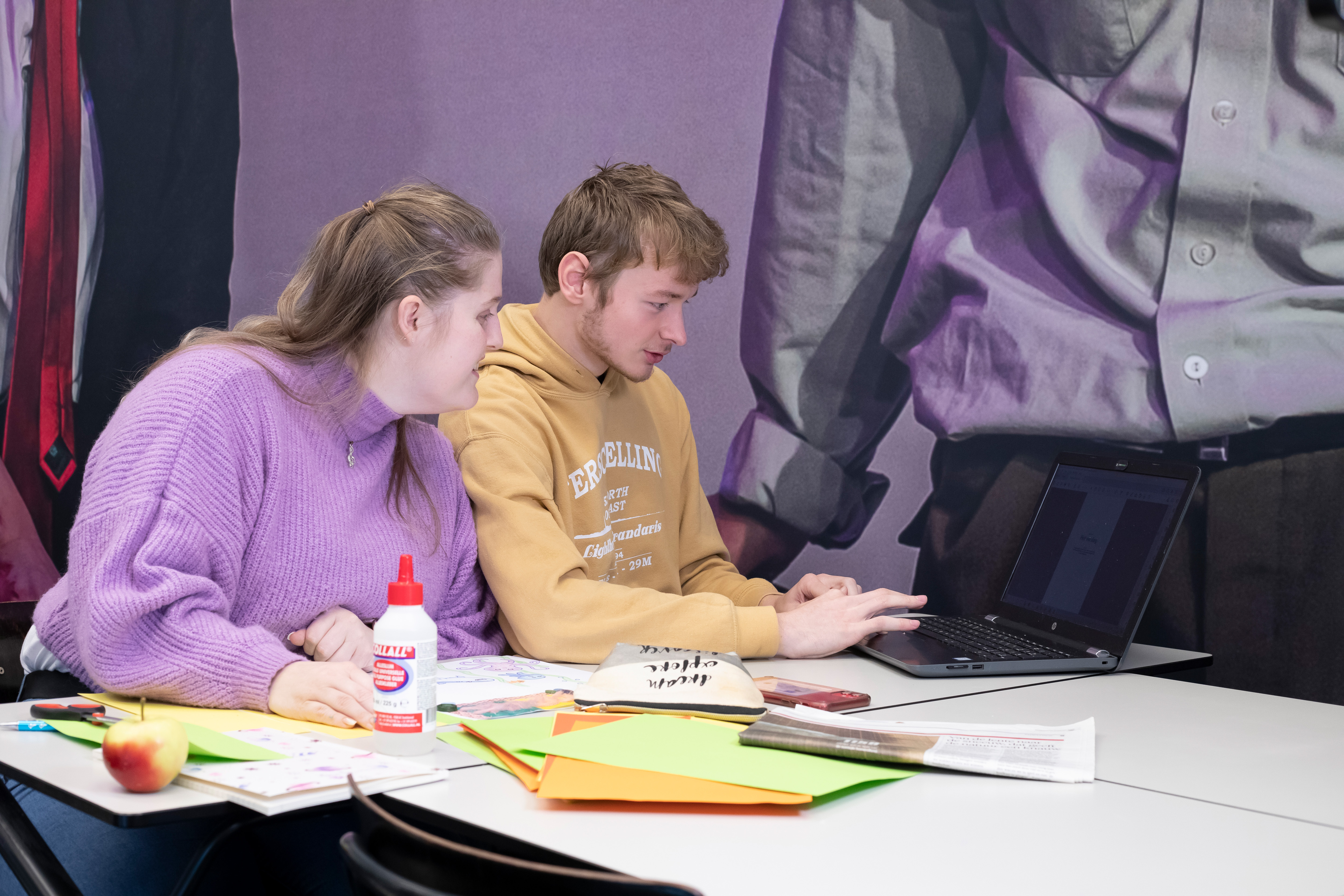 Twee studenten zitten achter een laptop met spullen om te knutselen op tafel